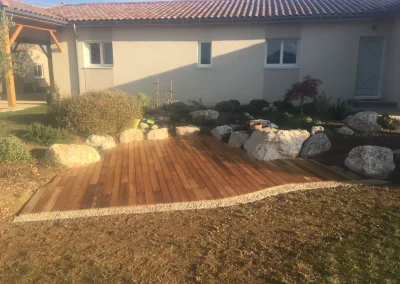 Terrasse en acacia lovée dans une rocaille à Charpey